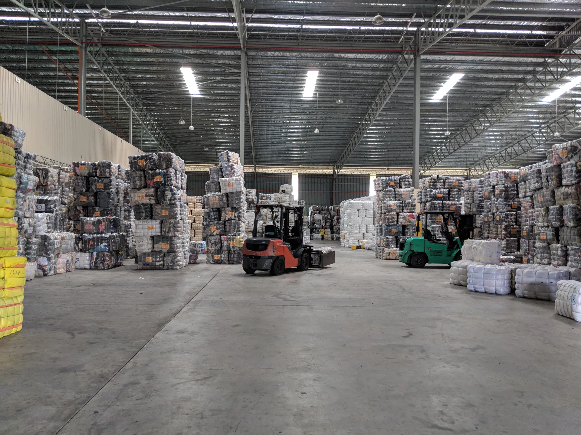 Modern warehouse facility with organized bales of sorted used clothing ready for export